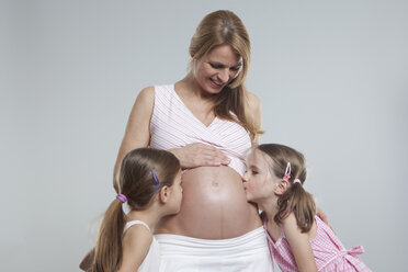 Töchter küssen sich auf dem Bauch ihrer schwangeren Mutter - RBF000451