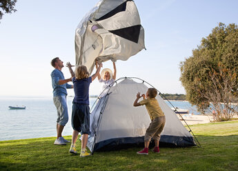 Croatia, Zadar, Family putting up tent at beach - HSIF000124