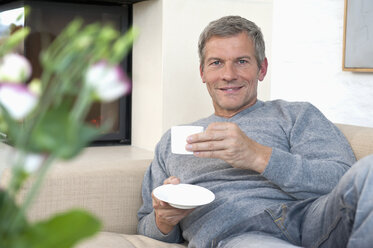 Germany, Munich, Mature man drinking coffee at home, portrait - NHF001299