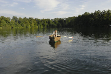 Germany, Bavaria, Wesslinger See, Business man rowing boat in lake after work - CRF002012