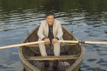 Germany, Bavaria, Wesslinger See, Business man rowing boat in lake after work - CRF002014