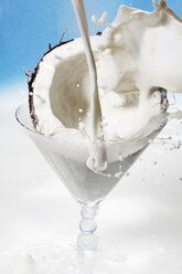 Coconut milk splashing on coconut in martini glass - CSF014262