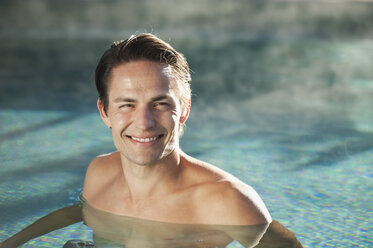 Italy, South Tyrol, Man in swimming pool of hotel urthaler, smiling - WESTF015887