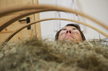 Italy, South Tyrol, Man having hay bath in hotel urthaler - WESTF015810