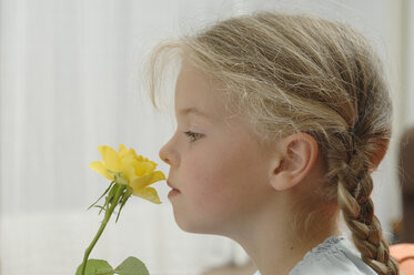 Germany, Bavaria, Girl smelling yellow rose - CRF002017