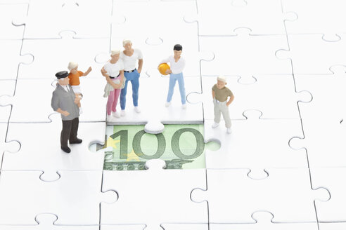 Figur, die auf einem Puzzleteil steht und den 100-Euro-Schein betrachtet - MAEF003022