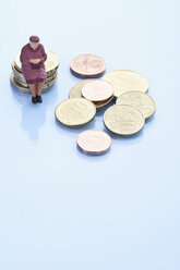 Weibliche Figur auf einem Stapel von Euro-Münzen sitzend - MAEF003030