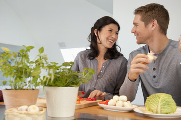 Germany, Munich, Man and woman cooking in kitchen, smiling - NHF001284