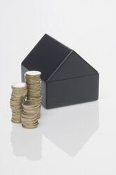 Miniatur-Haus mit Stapel von Münzen auf weißem Hintergrund - ASF004291