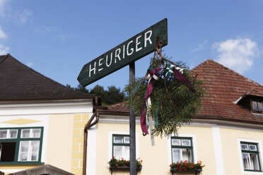 Austria, Lower Austria, Wachau, Waldviertel, Weissenkirchen, Text Heuriger on arrow sign with buildings - SIEF000237