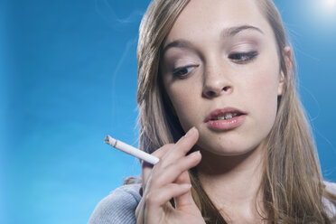 Teenage girl looking at cigarette, close up - WESTF016091