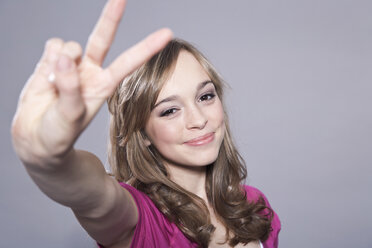 Teenage girl showing peace symbol, portrait - WESTF016102