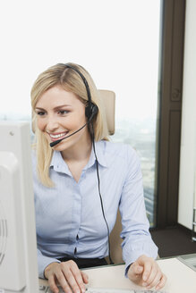 Germany, Frankfurt, Business woman wearing headset and using computer - SKF000439