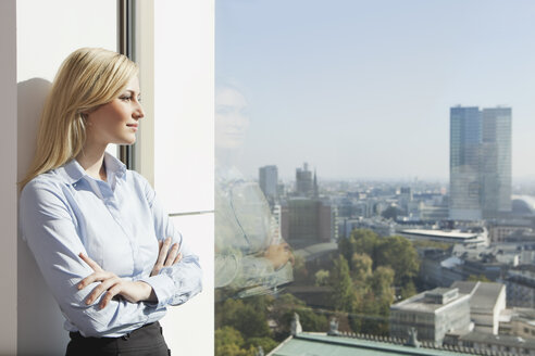 Germany, Frankfurt, Business woman looking through window - SKF000442