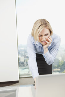 Germany, Frankfurt, Business woman using laptop in office - SKF000451