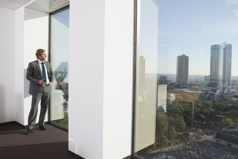 Germany, Frankfurt, Businessman using phone in office - SKF000469