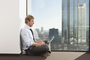 Germany, Frankfurt, Businessman using laptop in office - SKF000472