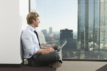 Germany, Frankfurt, Businessman using laptop in office - SKF000473