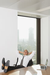 Deutschland, Frankfurt, Geschäftsmann in einem Büro mit Laptop auf dem Tisch - SKF000492