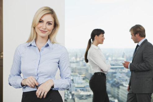 Germany, Frankfurt, Business woman smiling with business people talking in background - SKF000529