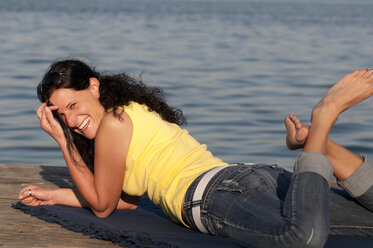 Mid adult woman resting on jetty, smiling, portrait - UMF000286