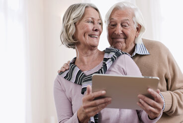 Germany, Wakendorf, Senior couple looking at picture frame, smiling - WESTF016228