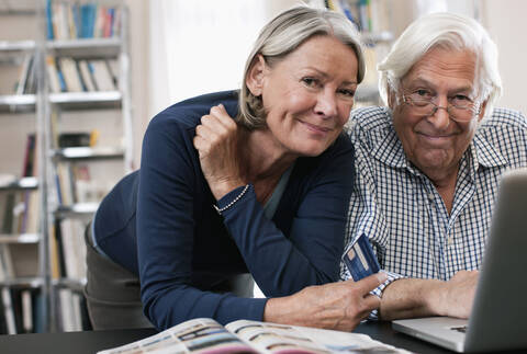 Germany, Wakendorf, Senior woman with credit card and man using laptop stock photo