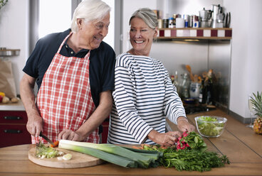 Deutschland, Wakendorf, Älteres Ehepaar beim Gemüseschneiden in der Küche - WESTF016248