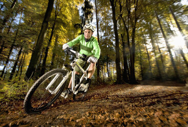 Deutschland, Bayern, Landshut, Junger Mann beim Mountainbiking im Wald - RNF000663