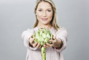 Mid adult woman holding artichoke, portrait - WESTF016261