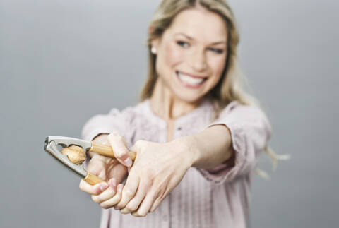 Mittlere erwachsene Frau knackt eine Walnuss mit einem Nussknacker, lizenzfreies Stockfoto