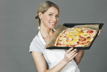 Mittlere erwachsene Frau hält Pizza in einem Tablett - WESTF016268