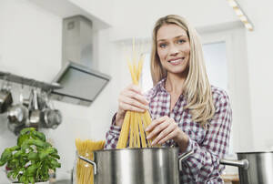 Deutschland, Köln, Frau kocht Spaghetti, Porträt, lächelnd - WESTF016272