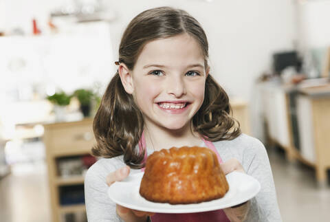 Deutschland, Köln, Mädchen hält Kuchen in einem Teller, Porträt, lizenzfreies Stockfoto