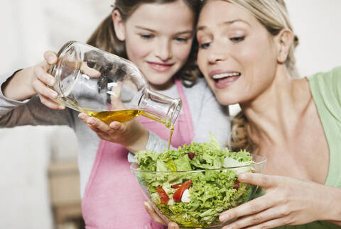 Deutschland, Köln, Mutter und Tochter bereiten Salat zu, lizenzfreies Stockfoto