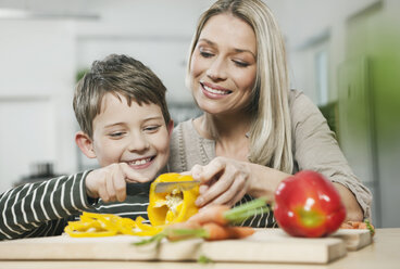 Germany, Cologne, Mother and son cutting vegetables in kitchen - WESTF016309