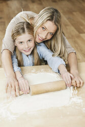 Germany, Cologne, Mother and daughter rolling dough, smiling, portrait - WESTF016320