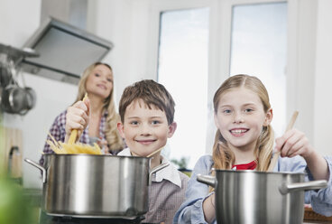 Deutschland, Köln, Kinder kochen Spaghetti in Küche, Mutter im Hintergrund - WESTF016348