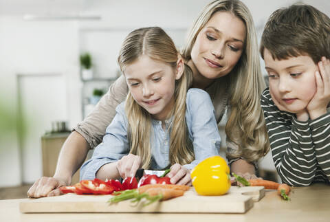 Deutschland, Köln, Mutter und Kinder schneiden Gemüse in der Küche, lizenzfreies Stockfoto