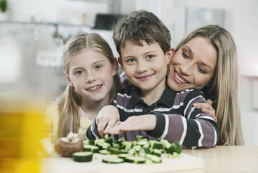 Deutschland, Köln, Mutter und Kinder schneiden Gemüse in der Küche - WESTF016356