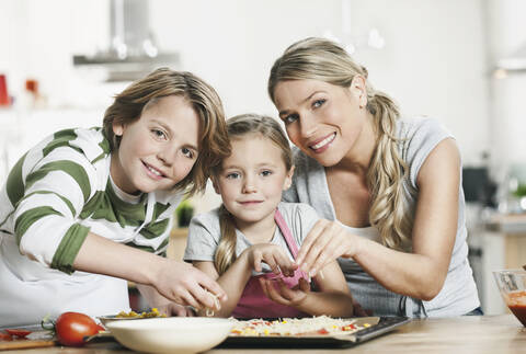 Deutschland, Köln, Mutter und Kinder beim Pizzabacken in der Küche, lizenzfreies Stockfoto