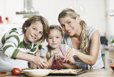 Germany, Cologne, Mother and children making pizza in kitchen - WESTF016364