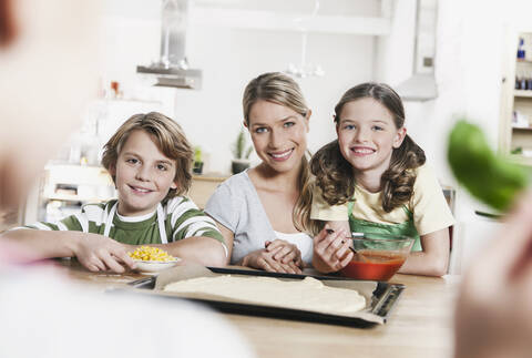 Deutschland, Köln, Mutter und Kinder beim Pizzabacken in der Küche, lizenzfreies Stockfoto