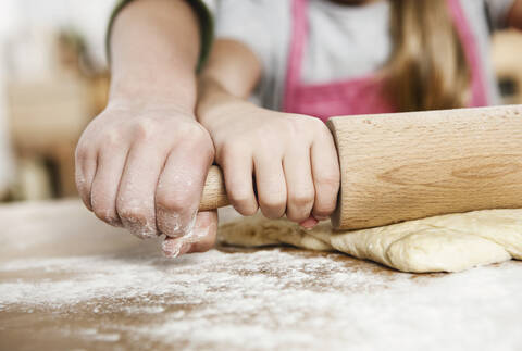 Germany, Cologne, Boy and girl rolling dough on kitchen worktop stock photo
