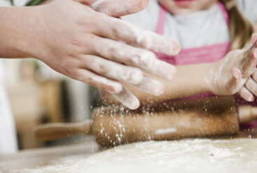 Germany, Cologne, Boy and girl rolling dough on kitchen worktop - WESTF016378
