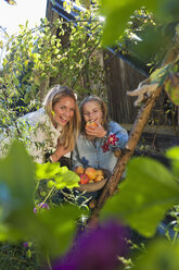Austria, Salzburg, Flachau, Girl with mother holding apple basket in farm garden - HHF003517
