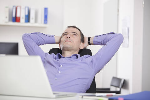 Deutschland, Bayern, München, Geschäftsmann entspannt im Büro, lizenzfreies Stockfoto