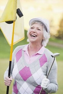 Italy, Kastelruth, Mature woman with golf club and golf flag on golf course, smiling - WESTF016420