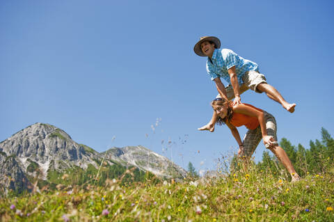 Austria, Salzburg Country, Altenmarkt-Zauchensee, Couple with leapfrog on mountains of Niedere Tauern stock photo