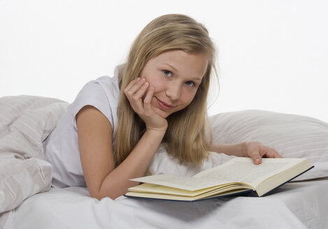 Girl lying on bed with book, portrait - WWF001875